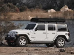 Namiot dachowy Wild Land Normandy Auto PRO 140 złożony na dachu białego Jeepa.